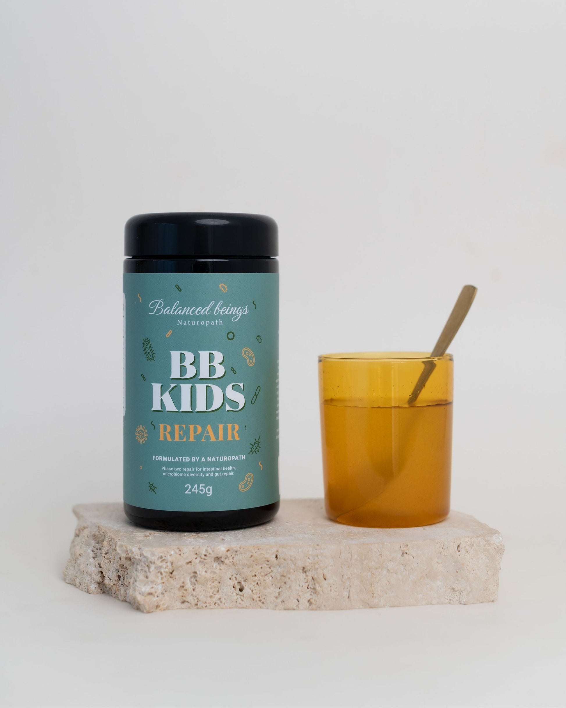 Balanced Beings BB Kids Repair supplement jar with a glass of juice on a white background