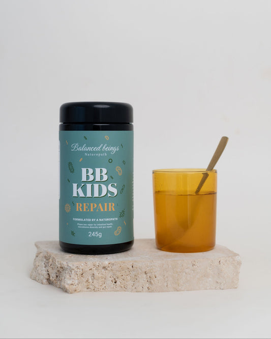Balanced Beasts BB Kids Repair supplement jar with a glass of juice on a white background